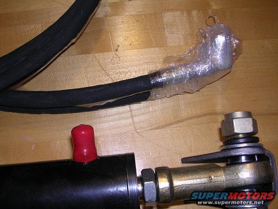 Black hose with a red cap and a metal joint with a nut, on a wooden surface