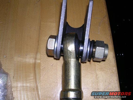 Close-up of a metal automotive suspension component with bolts and nuts