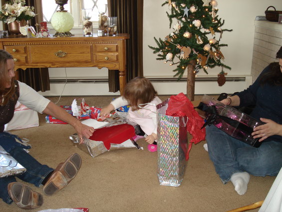 Christmas tree with gifts and people in a living room