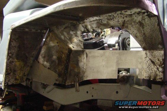 Vehicle chassis with exposed engine components and metalwork, showing signs of repair