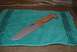 1991 Ford Bronco - A knife with a tan handle and a gray blade is placed on a teal towel with a decorative border.