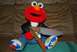 1991 Ford Bronco - A plush Elmo doll is dressed in a leather jacket and jeans, holding two knives in its lap.
