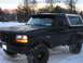 1995 Ford Bronco - A black Ford Bronco with a light bar and smiley face lights sits in the snow.