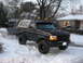 1995 Ford Bronco - Black 1995 Ford Bronco with a light bar and smiley face lights on the roof is parked in the snow, towing a trailer.