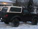 1995 Ford Bronco - A black Ford Bronco with a tan removable top is seen from the side in a snowy environment, with smoke coming from the exhaust.