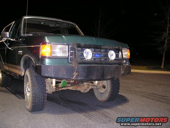 Green Ford Bronco with aftermarket winch bumper and auxiliary lights, front view