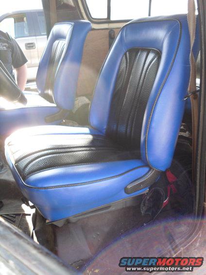 Blue and black vinyl bucket seats inside a vehicle, with a person visible in the background
