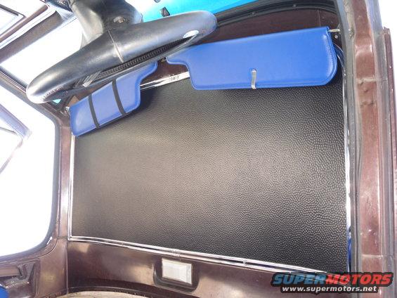 Interior view of a vehicle with blue sun visors and black textured paneling