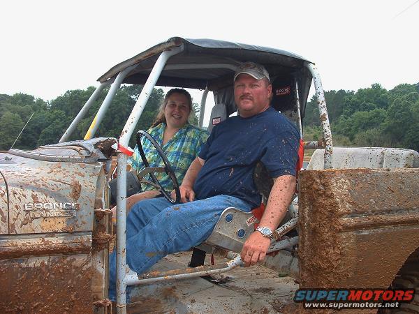 Mud-covered Ford Bronco Ranger interior with two people. The vehicle has a roll cage and is heavily modified