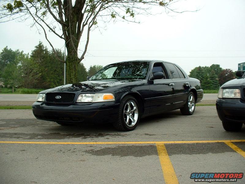 Dark sedan parked next to another dark sedan. The front of the sedan is visible