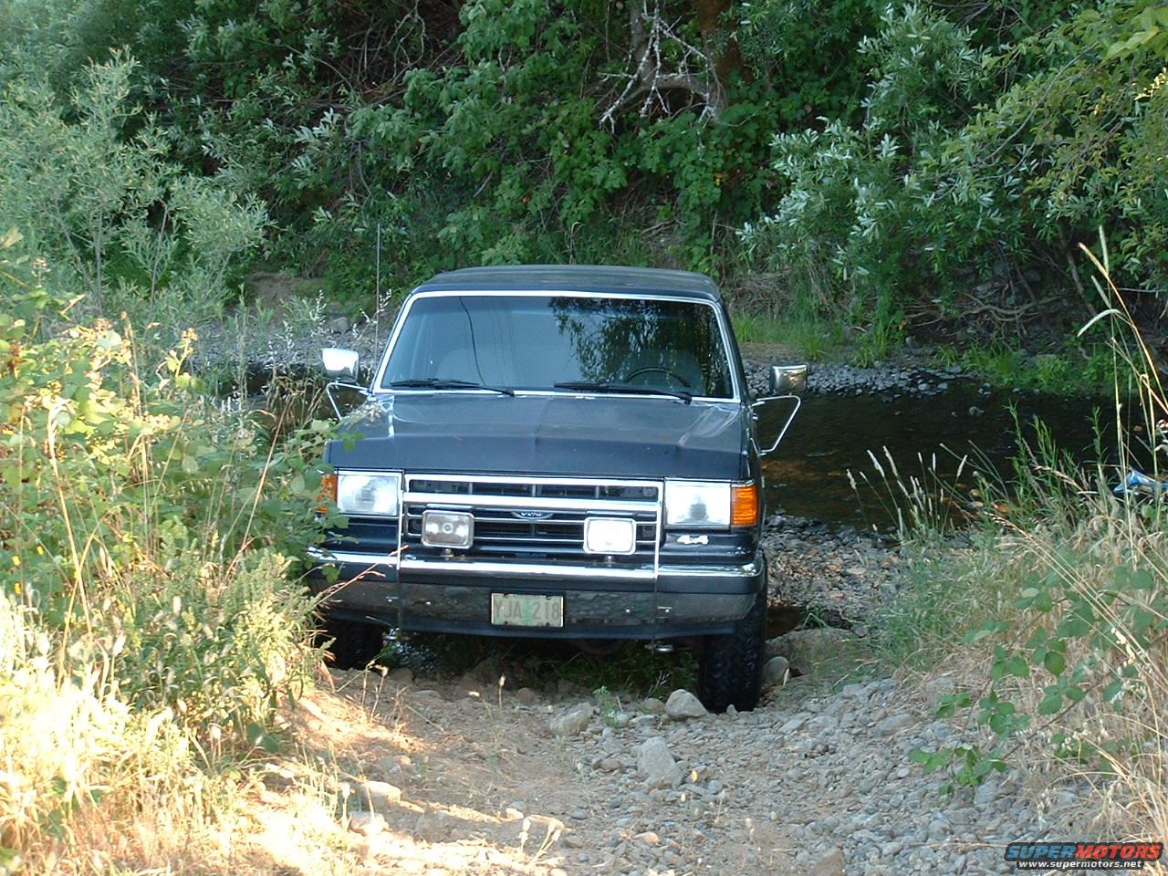 1991 Ford Bronco front view, dark blue, driving through stream