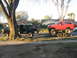 1987 Ford Bronco - A lifted red Ford Bronco is transported on a trailer by a black Ford pickup truck on a residential street.