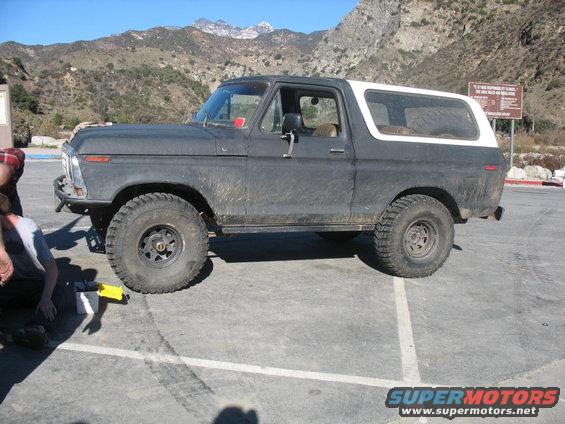 Dark gray and white Ford Bronco with off-road tires parked on asphalt