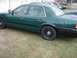 2000 Ford Crown Victoria - A green sedan is parked on grass, showing its side profile and black trim details.