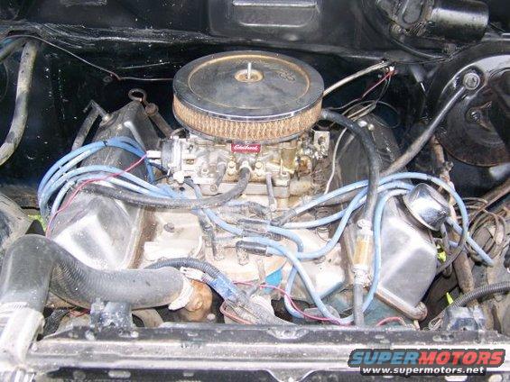 Engine bay showing carburetor, air filter, spark plug wires, and radiator hoses