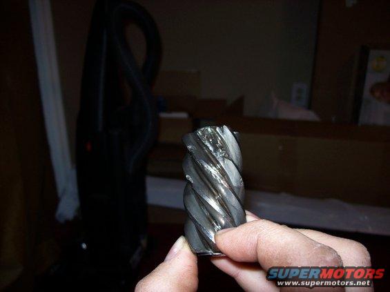 Worn gear held in hand, showing spiral teeth