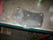 1995 Ford C-350 (Centurion Conversions) - Metal bracket with bolt holes sits on a workbench next to some hardware.