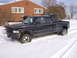 1995 Dodge 3500 - A black 1995 Dodge 3500 pickup truck is stuck in the snow with dual rear wheels visible.