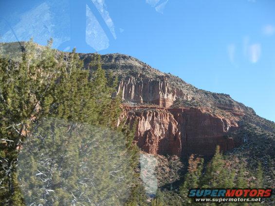 View of a rocky mountain with trees in the foreground, seen through a window