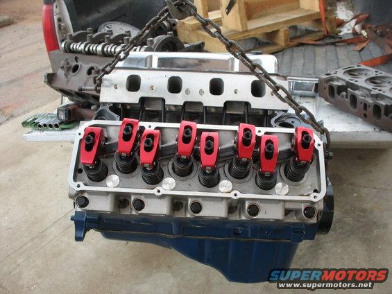 Engine block with red rocker arms and chrome intake manifold, suspended by chains