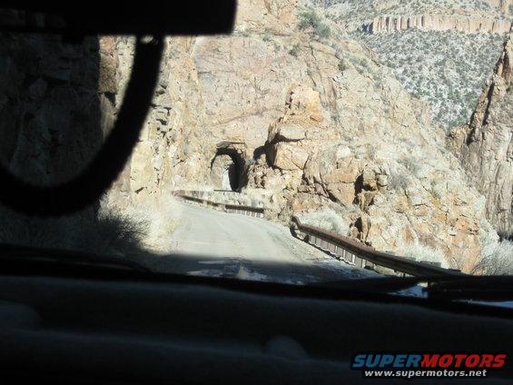 driving on a road towards a tunnel in a rocky mountain landscape