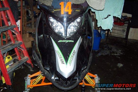 Front view of a black Arctic Cat snowmobile with orange number 14 on the hood