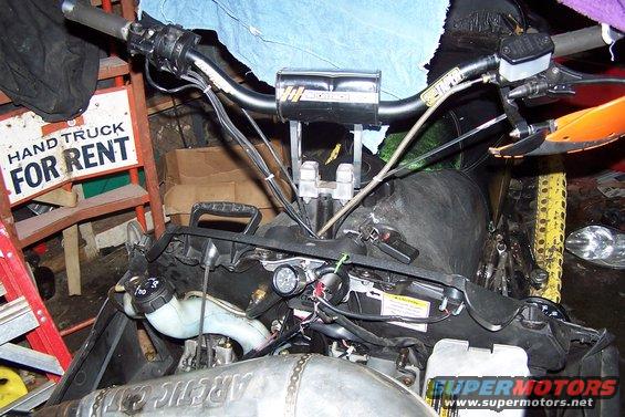 Snowmobile engine and handlebars with "HAND TRUCK FOR RENT" sign in background