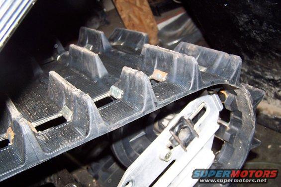 Snowmobile track with aggressive lugs and metal reinforcement