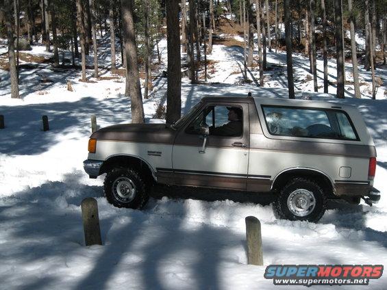 Side view of a 1993 Ford Bronco driving through snow