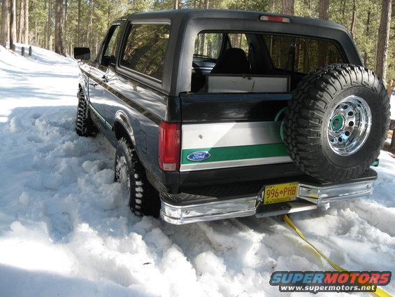 1993 Ford Bronco stuck in snow, rear view with spare tire mounted