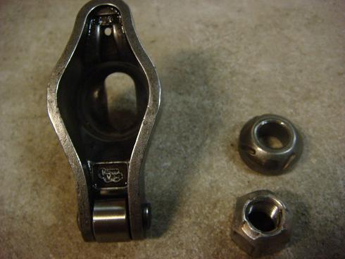 Engine valve rocker arm with roller and two nuts on a textured surface