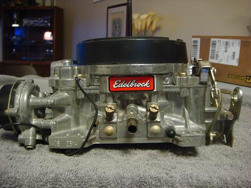 Carburetor with red Edelbrock logo, silver metal body, black top, and wires