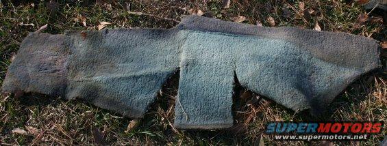 Worn, cut piece of blue and gray carpet lying on grass and leaves
