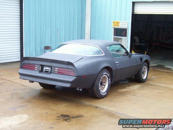 1978 Pontiac Trans Am in primer, parked outside a garage