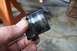 1990 Ford Bronco - Close-up of a greasy ball joint part being held by a hand, with a jack stand visible.