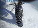 1995 Ford Mustang - A motorcycle tire equipped with studs is shown on a snow-covered ground, with a license plate in the background.