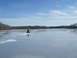1995 Ford Mustang - An ATV rides across a frozen lake under a partly cloudy sky, with trees lining the distant shore.