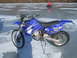 1995 Ford Mustang - A blue Yamaha dirt bike equipped with studded tires sits on a frozen surface, with an ATV visible in the distance.