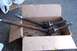 1990 Ford Bronco - Two axle shafts, likely for a 4WD vehicle, sit in a cardboard box. One shaft has a ribbed boot.