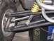 2006 Ford F1 - Close-up of go-kart rear suspension components and a tire, with a warning label on a bucket in the background.