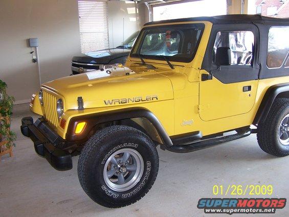 Yellow 2001 Jeep TJ Wrangler with black soft top, parked in a garage