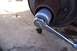 1990 Ford Bronco - A socket wrench is used to work on a vehicle's hub assembly, likely for a ball joint replacement.