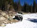 1987 Suzuki Samurai - A white 1987 Suzuki Samurai tackles a challenging off-road course with snow and rocks.