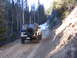 1987 Suzuki Samurai - A white Suzuki Samurai navigates a narrow dirt road in a wooded, mountainous area.