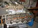 1970 Ford Mustang - The internal components of a V8 engine are visible, including the camshaft, rocker arms, and valves, with a dual carburetor setup.