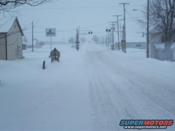 Snow-covered road with a building on the left and utility poles lining the right