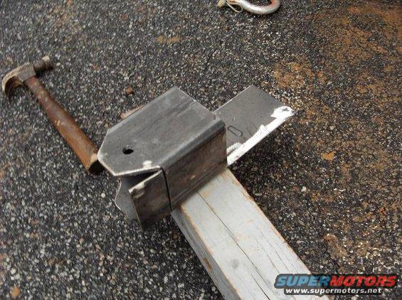 Metal bracket on wood with hammer nearby