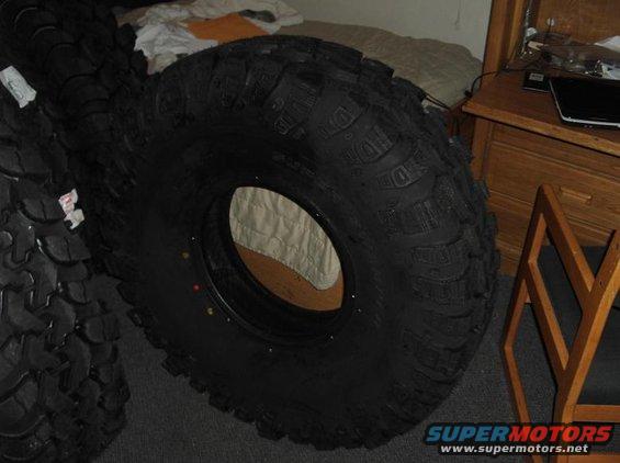 Stack of large off-road tires, one in foreground