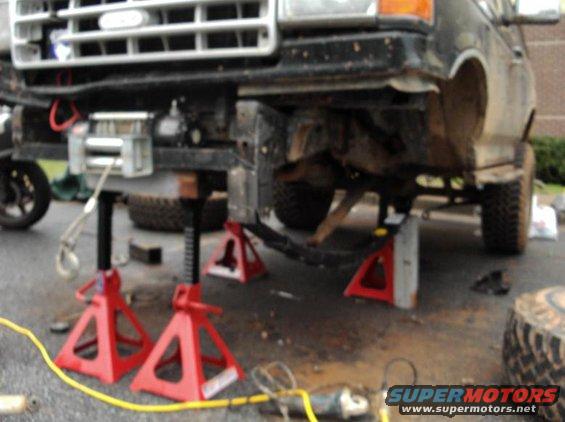 Black Ford truck front end on jack stands, with winch and off-road tires visible