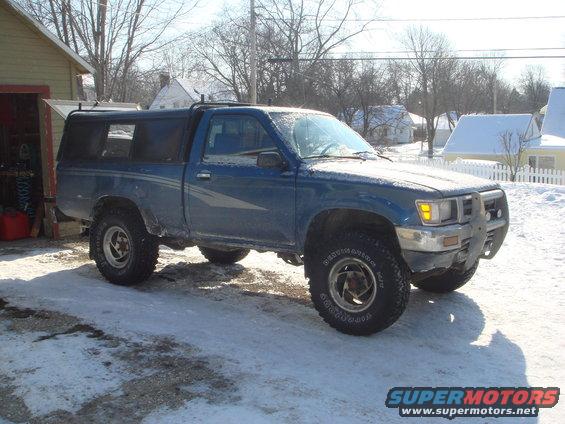 Blue 1991 Toyota Tacoma pickup truck with a camper shell parked in the snow